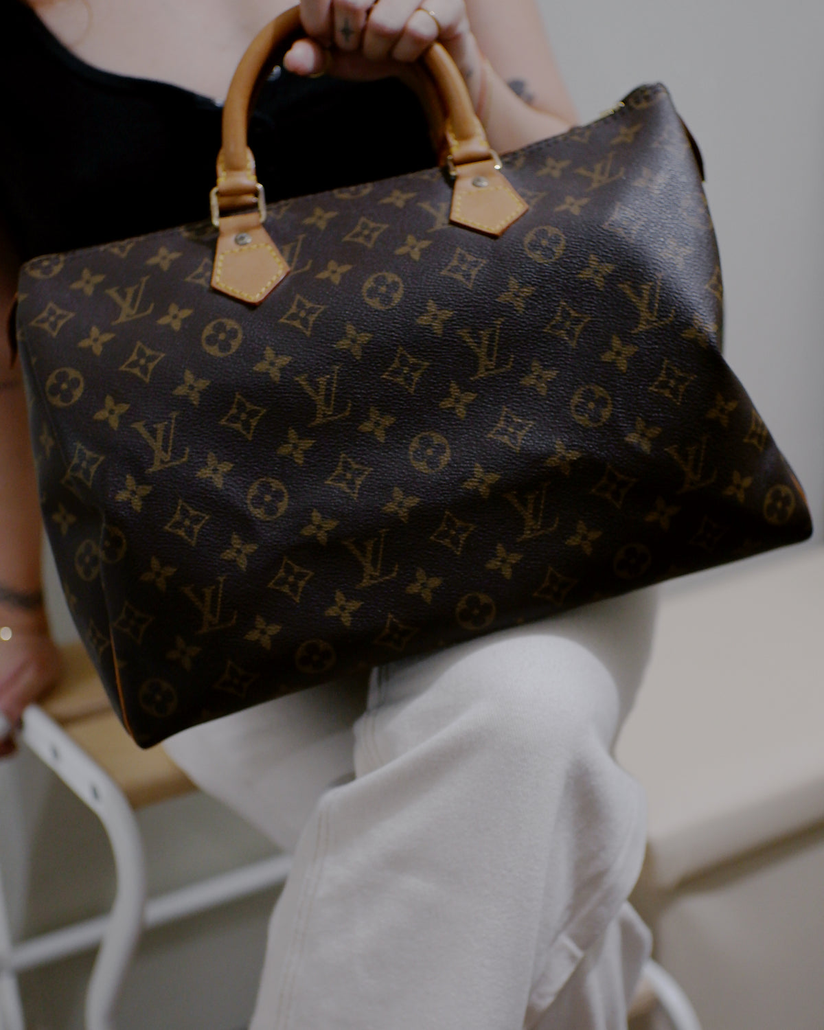 Person holding a Louis Vuitton monogram handbag with a blurred background